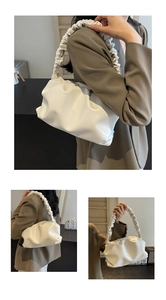 Detail of artistic pleated cloud handbag featuring textured faux leather and ruched handle