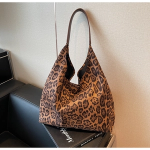Chic leopard print faux suede tote bag with brown leather straps on a sofa