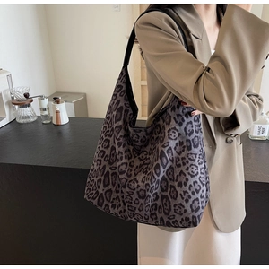 Close-up of leopard print canvas tote bag with black leather handle in lifestyle setting