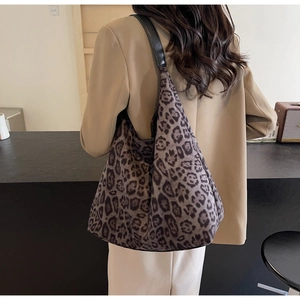 Detailed view of leopard print hobo bag with black leather shoulder strap on a model