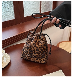 Détail du sac seau léopard avec cordon de serrage et logo de marque sur une table en bois