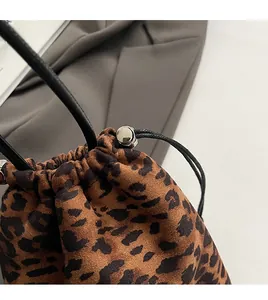 Détail d'un sac seau léopard avec fermeture par cordon et boucle métallique argentée