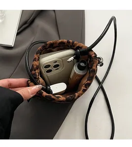 Vue détaillée du rangement interne du sac seau léopard avec téléphone et produits de beauté