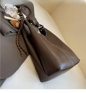 Detail of vintage brown leather tote bag with contrast white stitching and baseball charm
