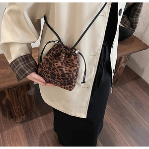 Détail du sac seau à imprimé léopard avec fermeture à cordon et fine bandoulière noire