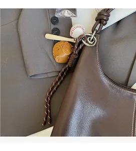 Detail of dark brown leather hobo bag with a decorative baseball-themed charm set