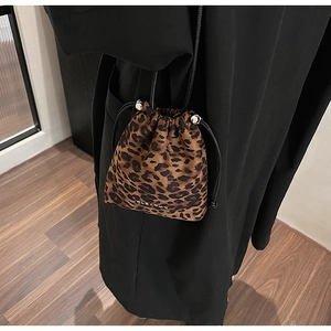 Détail du sac seau à imprimé léopard avec cordon et logo argenté sur manteau noir