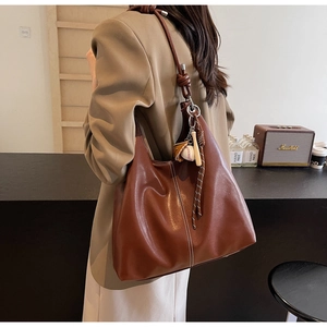 Detail of vintage brown leather hobo bag featuring baseball charms and stitching