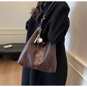 Brown faux leather tote bag detail with white contrast stitching and baseball charm