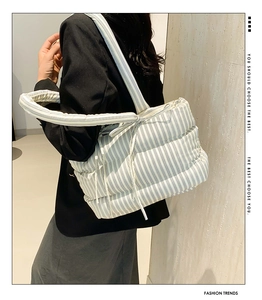 Détail d'un grand sac cabas rayé matelassé avec un nœud décoratif sur la bandoulière