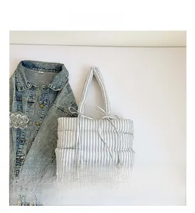 Détail du sac cabas matelassé à rayures bleues et blanches avec nœud décoratif