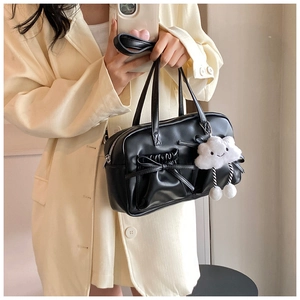 Detail of black leather bow bag with a white plush cloud charm and ruffled texture