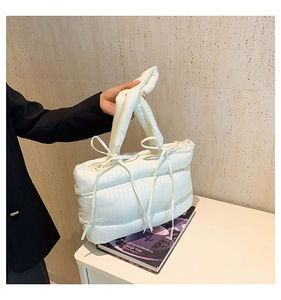 Détail du sac cabas matelassé blanc avec rubans à nœuds et finition satinée