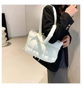 Détail du sac cabas matelassé blanc avec nœuds porté à l'épaule par le mannequin