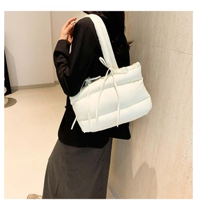 Vue latérale d'un sac à bandoulière matelassé blanc avec des rubans décoratifs sur un mannequin