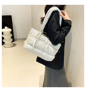 Sac cabas matelassé moderne à rayures noires et blanches porté à l'épaule par un mannequin