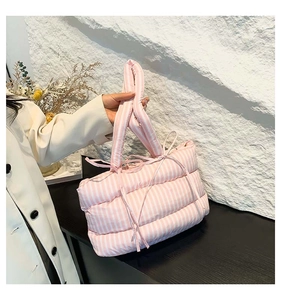 Gros plan du sac cabas matelassé rose à rayures avec des nœuds décoratifs sur l'anse