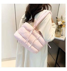 Détail du sac fourre-tout matelassé à rayures roses porté sur un manteau beige