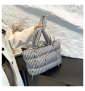 Détail du sac cabas matelassé à rayures noires et blanches avec nœuds latéraux élégants