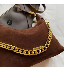 Close-up of matte brown suede shoulder bag with chunky gold chain detail