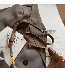 Detail of adjustable shoulder strap and golden buckle on brown suede leather handbag