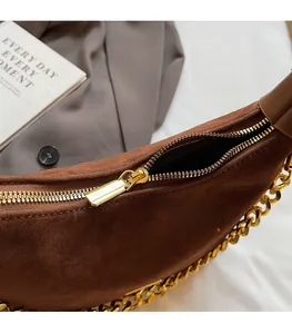 Detail of a brown faux suede handbag showing the smooth golden metal zipper and chain
