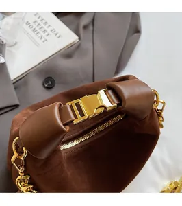 Macro shot of brown suede bag featuring gold metal buckle and chunky chain shoulder strap