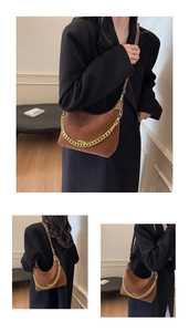 Detailed view of brown suede crescent bag with gold chain and metal brand plate