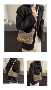 Detail of grey suede hobo bag with chunky gold chain strap and curved modern design
