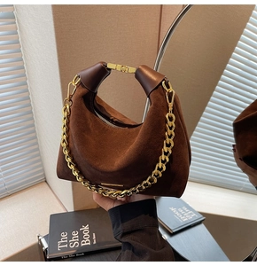Détail du sac hobo en suède avec chaîne dorée et finitions de poignée en cuir poli