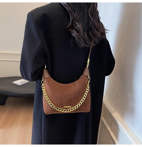 Close-up of brown suede hobo bag with gold metal trim and chunky chain strap