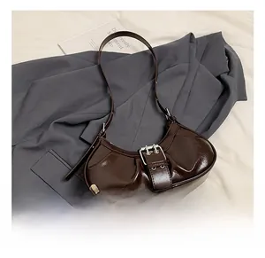 Macro shot of dark brown glossy leather crescent bag with silver belt buckle detail