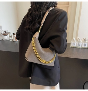 Detail of grey suede shoulder bag featuring a chunky gold chain strap and smooth matte texture