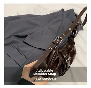 Detail of dark brown glossy leather bag with adjustable strap and retro metal buckles