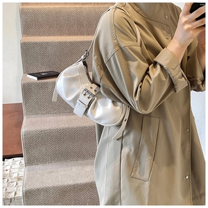 Close-up of a white pleated baguette bag with metal buckle detail on a female model