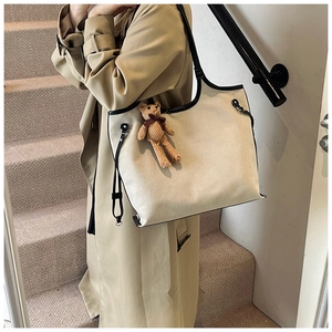 Canvas tote bag side view on model featuring black trim and cute brown bear pendant