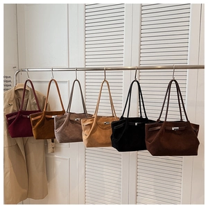 Multiple colors of suede tote bags hanging on a rack for autumn collection display