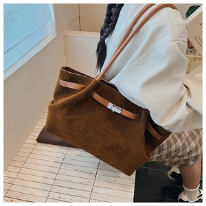 Detail of dark brown matte leather tote bag with silver buckle and light brown handle