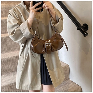 Detail of dark brown faux leather baguette bag with ruched texture and silver metal eyelets