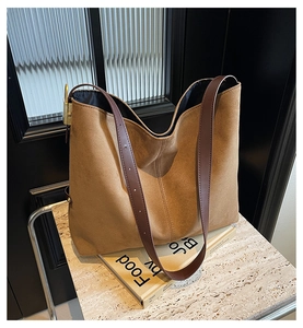 Close-up of minimalist brown suede tote bag with leather straps on stone surface