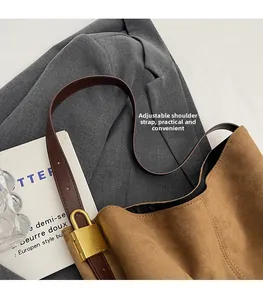 Detail of adjustable leather strap and golden buckle on brown suede bucket bag
