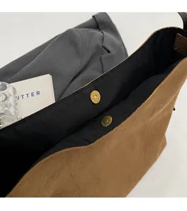 Close-up of the magnetic buckle closure on a brown suede tote bag for women