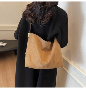 Detail of suede hobo tote bag with golden buckle on a black cashmere coat