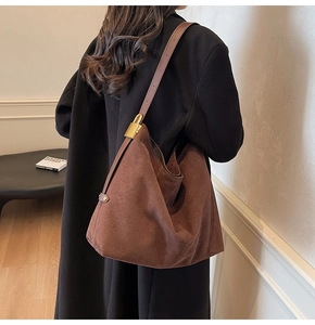 Close-up of brown suede hobo bag with gold hardware detail and leather strap