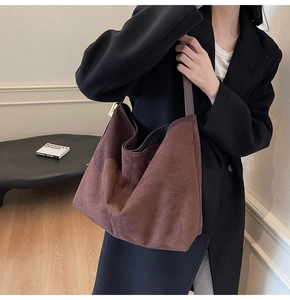 Close-up of the vintage brown suede texture and minimalist shoulder strap of the bucket bag