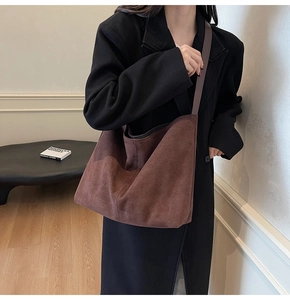 Detail of a large dark brown suede tote bag featuring a textured matte hobo style finish