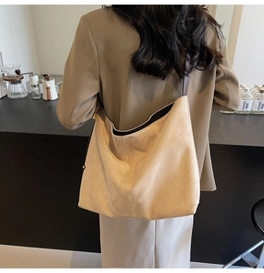 Minimalist beige suede hobo bag shown from the back perspective on a professional model