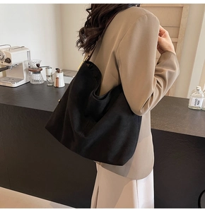 Detailed view of matte black suede bucket bag with gold buckle on a model shoulder
