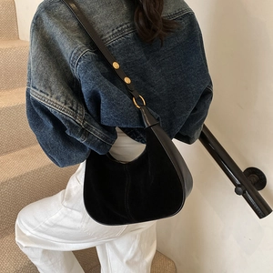 Détail du sac demi-lune en cuir noir et daim avec rivets dorés sur la bandoulière