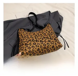 Detail view of leopard print shoulder bag featuring thin black straps and side drawstring